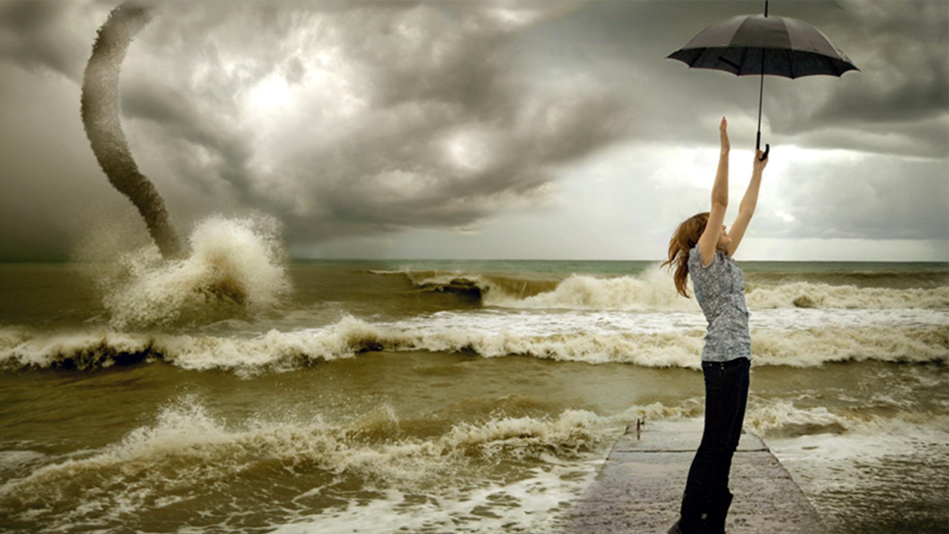 Photograph of a young woman holding an umbrella with the sea in the background
