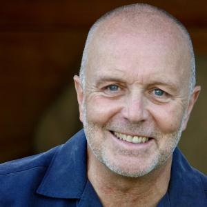 Man with short hair smiling wearing a blue shirt