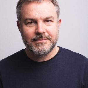 Man with short hair, facial hair and a black top