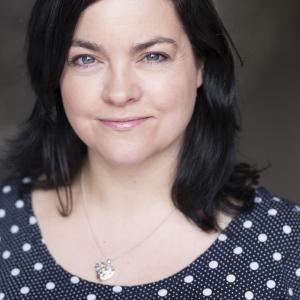 Woman with black shoulder length hair wearing a black top with white spots