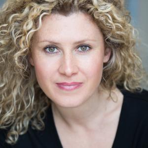 Headshot of woman with curly blonde hair wearing a black top